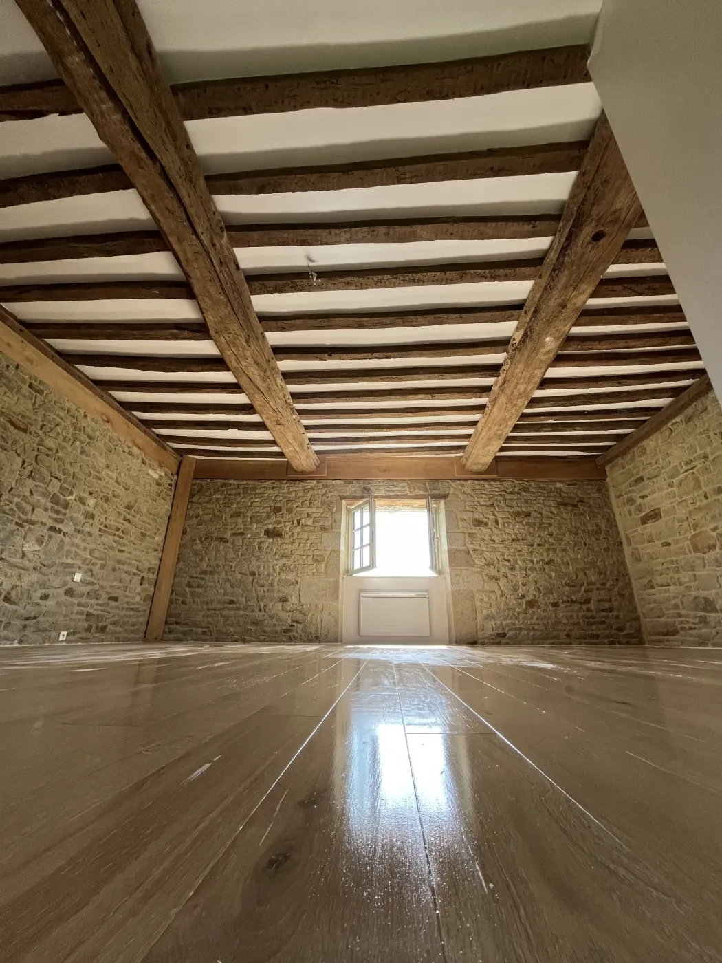 Pièce d'une maison ancienne aux murs en pierre et poutres apparentes, avec un sol neuf, à Vire Normandie